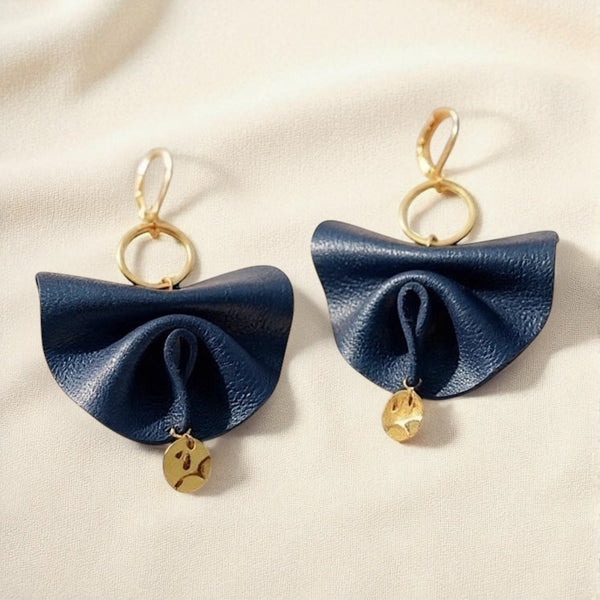 Grandes boucles d'oreilles dorées en éventails de cuir plissé recyclé bleu marine satiné, sur fond beige