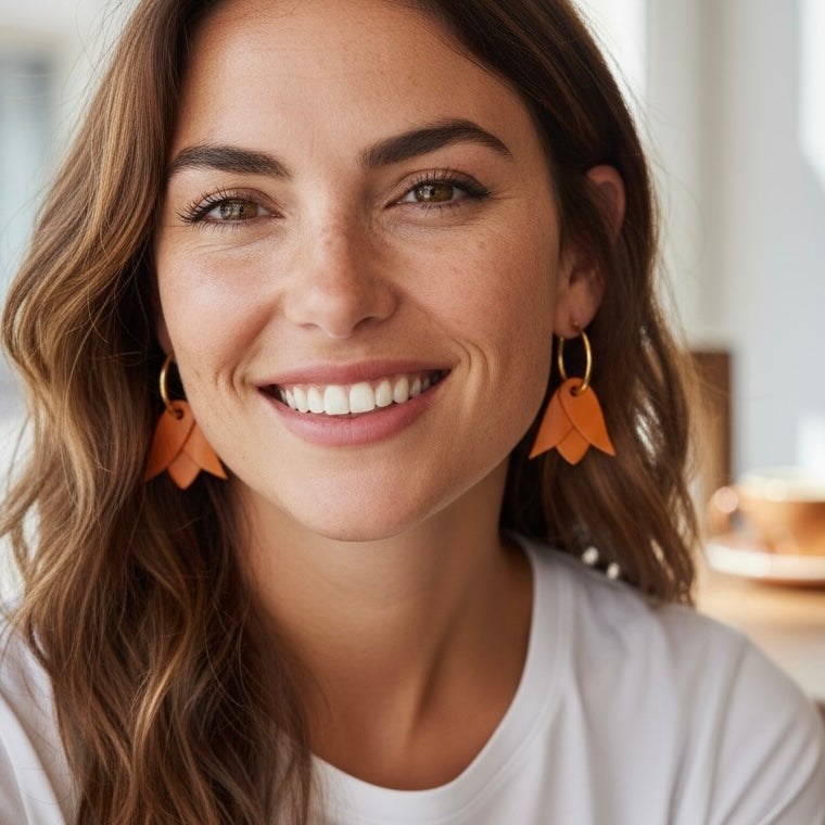 Boucles d'oreilles créoles dorées avec pendentifs légers en cuir orange mandarine en forme de tulipe, portées aux oreilles