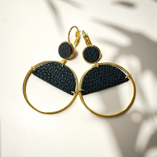 Paire de boucles d'oreilles créoles dorées Nune modèle Lua avec cuir noir grainé, sur fond cuir beige doré