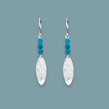 Charger l&#39;image dans la galerie, Boucles d&#39;oreilles fines en pointe en métal martelé doré à l&#39;or fin et petites perles d&#39;apatite bleue, sur fond bleu gris

