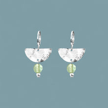 Charger l&#39;image dans la galerie, Petites boucles d&#39;oreilles pendantes, de forme demi-lune, en métal martelé argenté et perles de fluorite vert d&#39;eau, sur fond bleu gris
