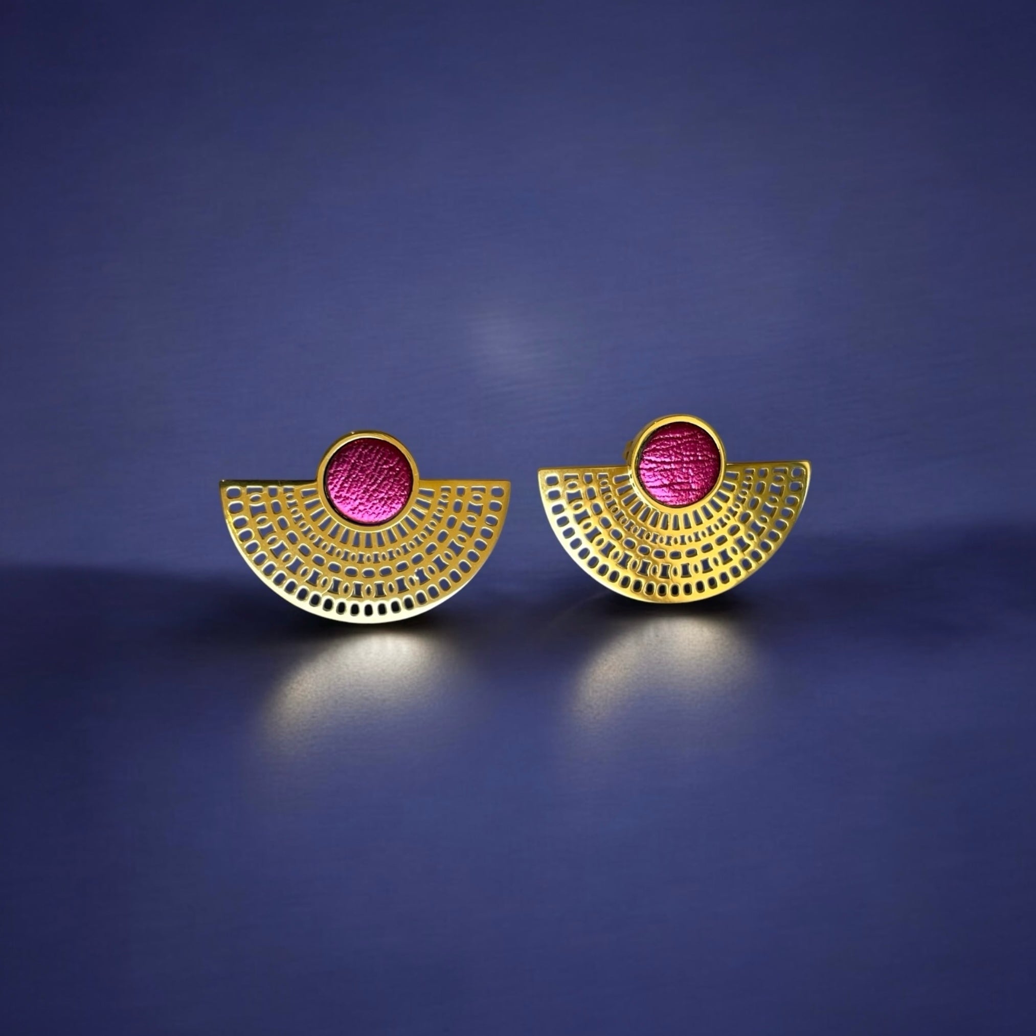 boucles d'oreilles puces dorées Nune modèle Amphea en cuir rose fushia métallisé, sur fond bleu