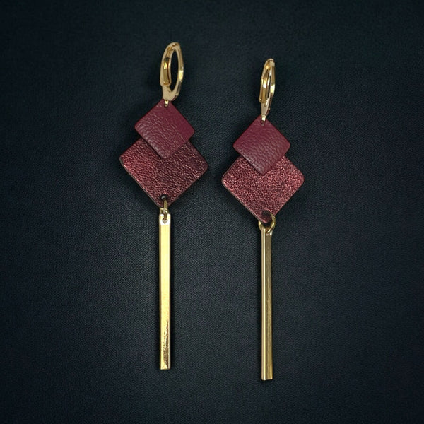 boucles d'oreilles dorées Nune modèle Ada avec duo de losanges en cuirs pourpre et grenat métallisé et longue tige fine dorée sur fond blanc
