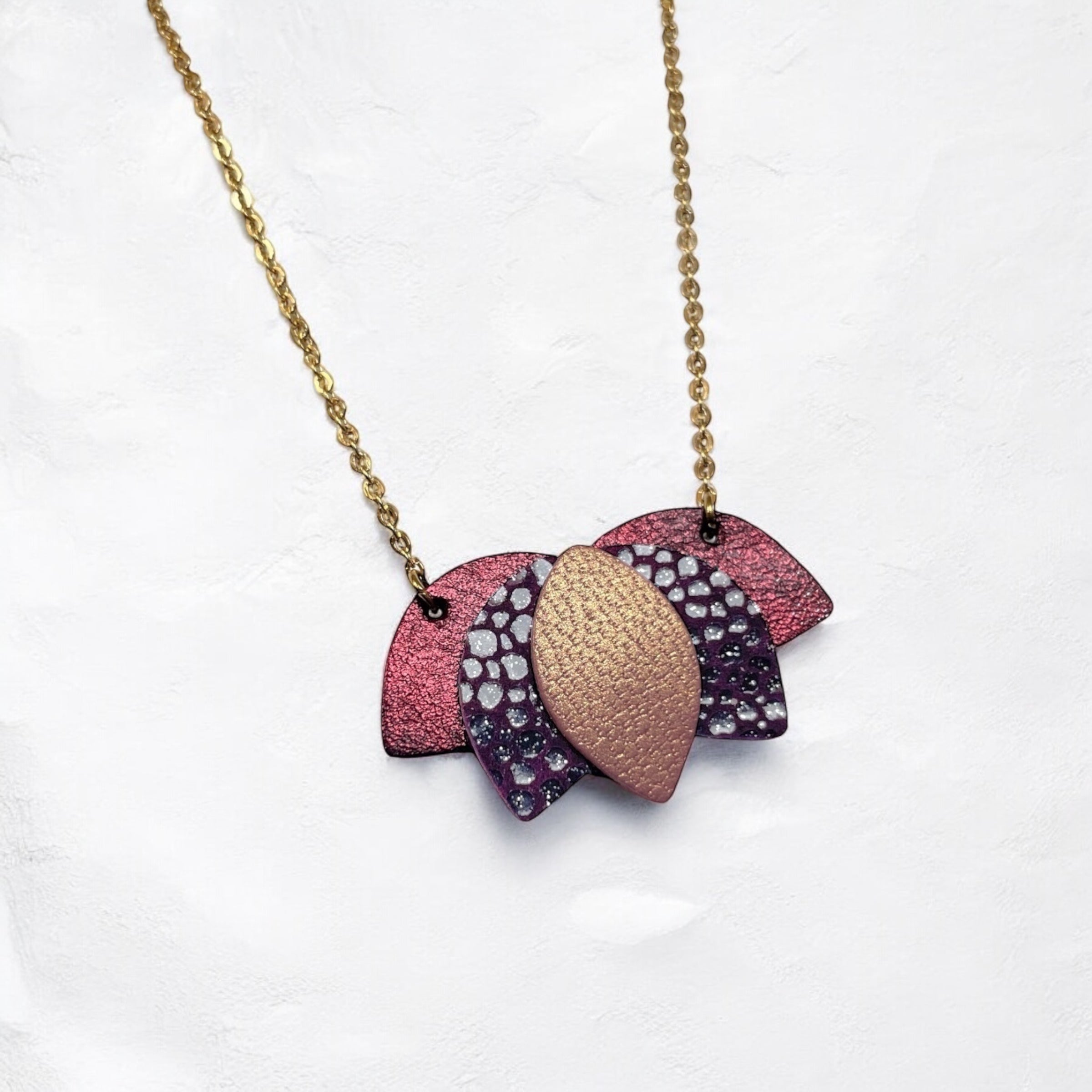 Collier dorée en forme de fleur de Lotus en cuirs grenat métallisé, prune irisé et vieux rose nacré sur fond blanc