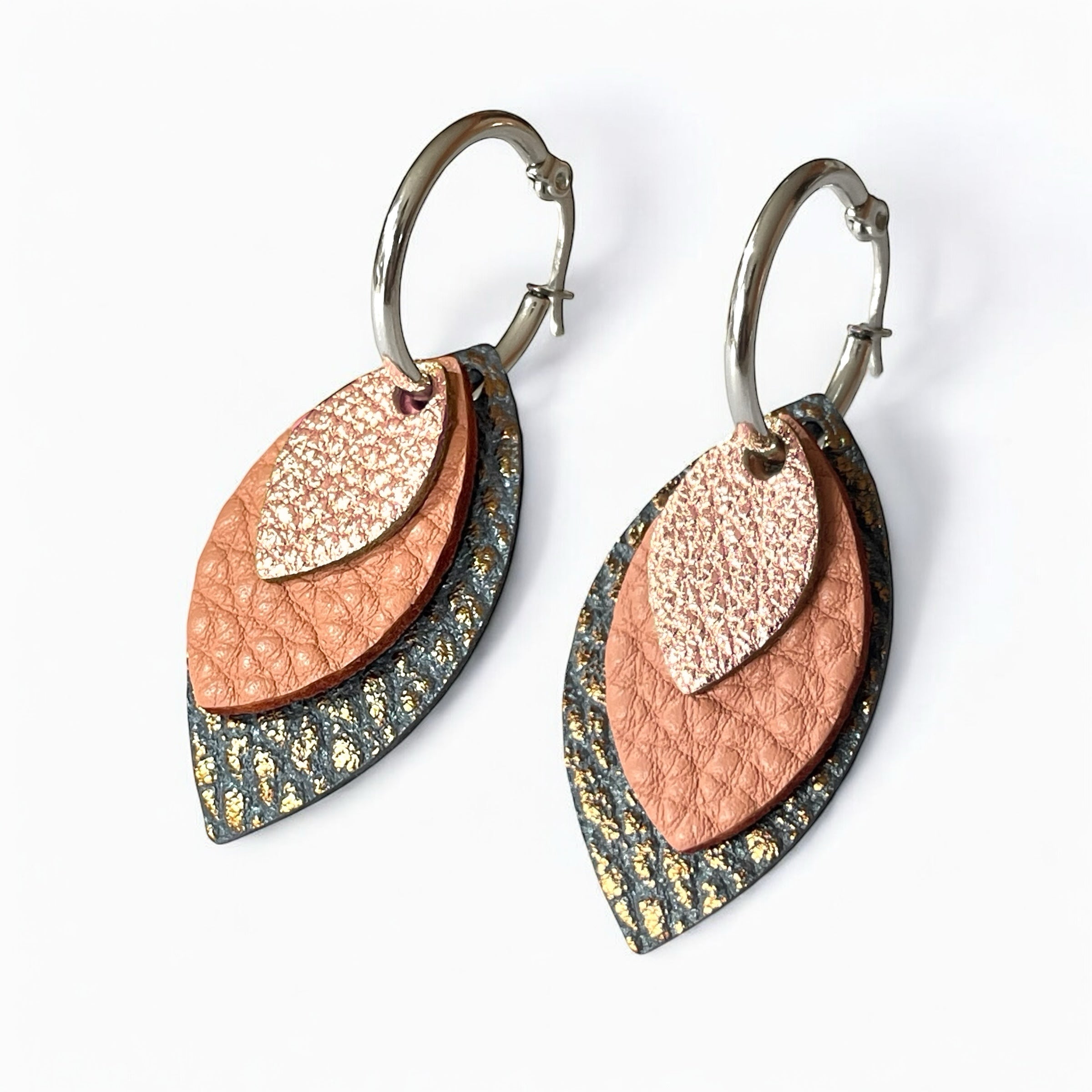 Créoles argentées avec pendentifs modulables en forme de feuilles en cuirs rose pâle métallisé, rose thé grainé et gris mordoré grainé, sur fond blanc
