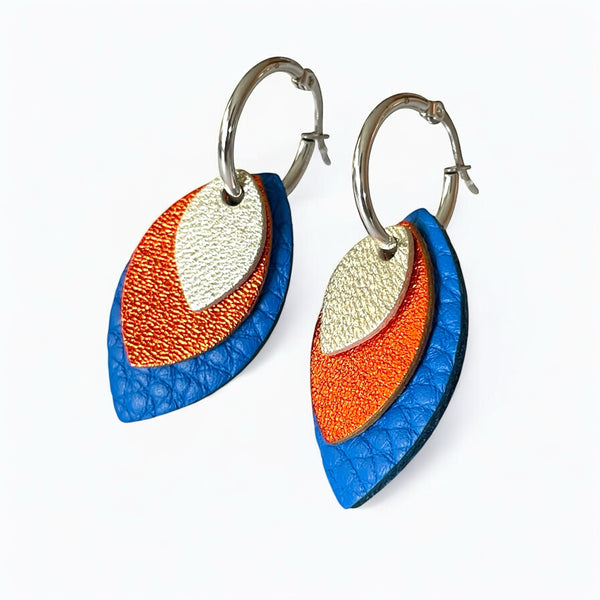 Créoles argentées avec pendentifs modulables en forme de feuilles en cuirs argent, orange sanguine métallisé et bleu roi grainé, sur fond blanc