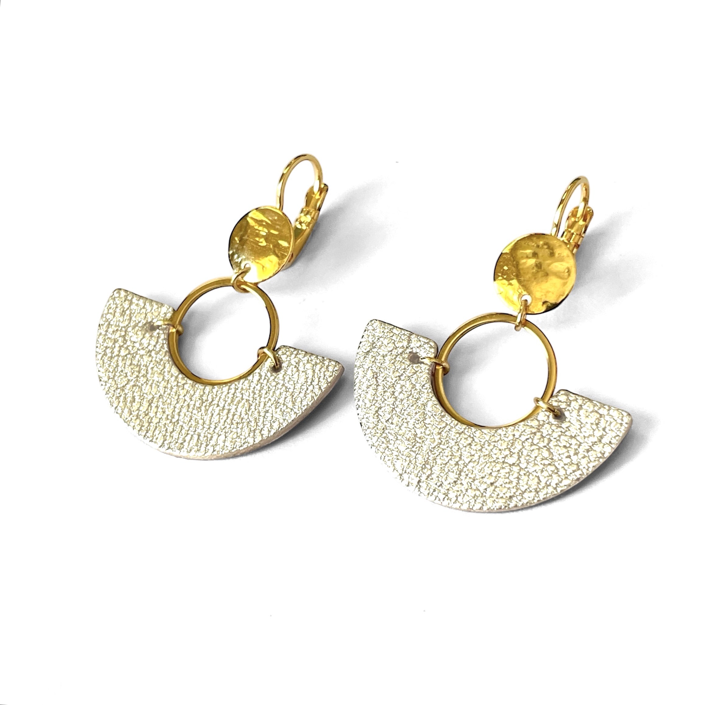 paire de boucles d'oreilles dorées pendantes en forme de demi-lunes en cuir bleu argent, sur fond blanc
