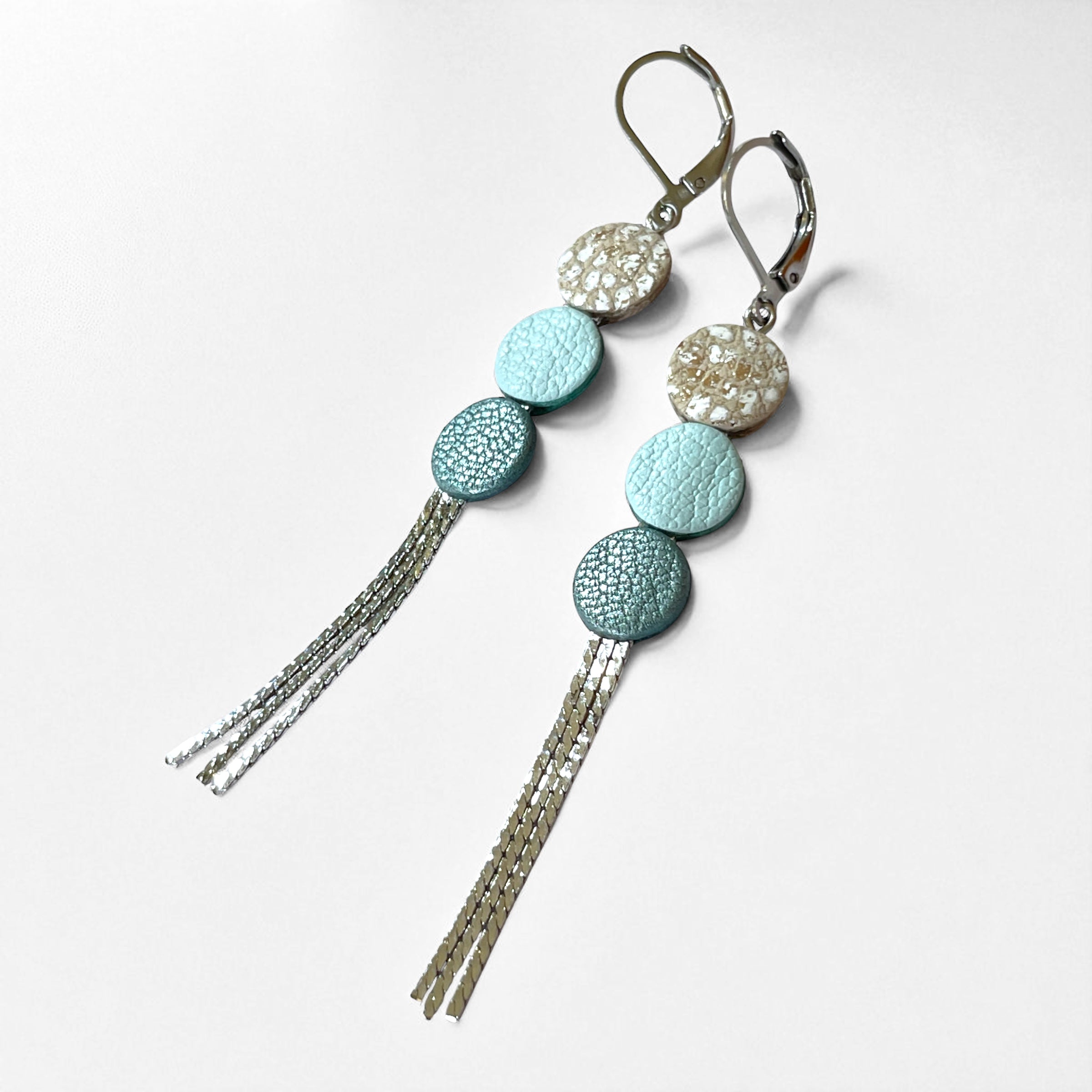Longues et fines boucles d'oreilles à franges argentées avec 3 petits disques de cuir recyclé blanc moucheté or et argent, bleu nuage et bleu gris nacré, sur fond blanc
