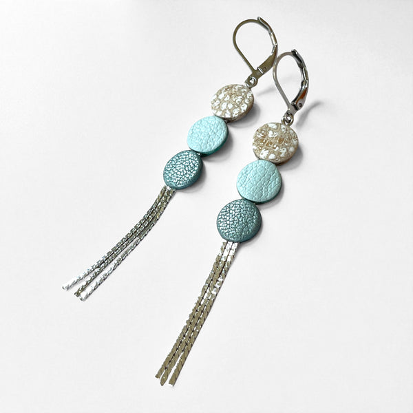 Longues et fines boucles d'oreilles à franges argentées avec 3 petits disques de cuir recyclé blanc moucheté or et argent, bleu nuage et bleu gris nacré, sur fond blanc