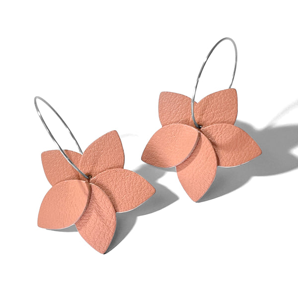 Petites boucles d'oreilles en forme de fleurs en cuir rose pêche, montées sur créoles argentées, sur fond blanc