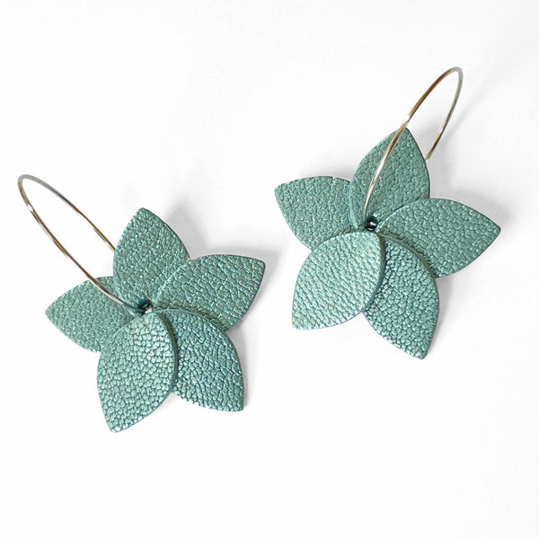 Petites boucles d'oreilles en forme de fleurs en cuir bleu gris nacré, montées sur créoles argentées, sur fond blanc