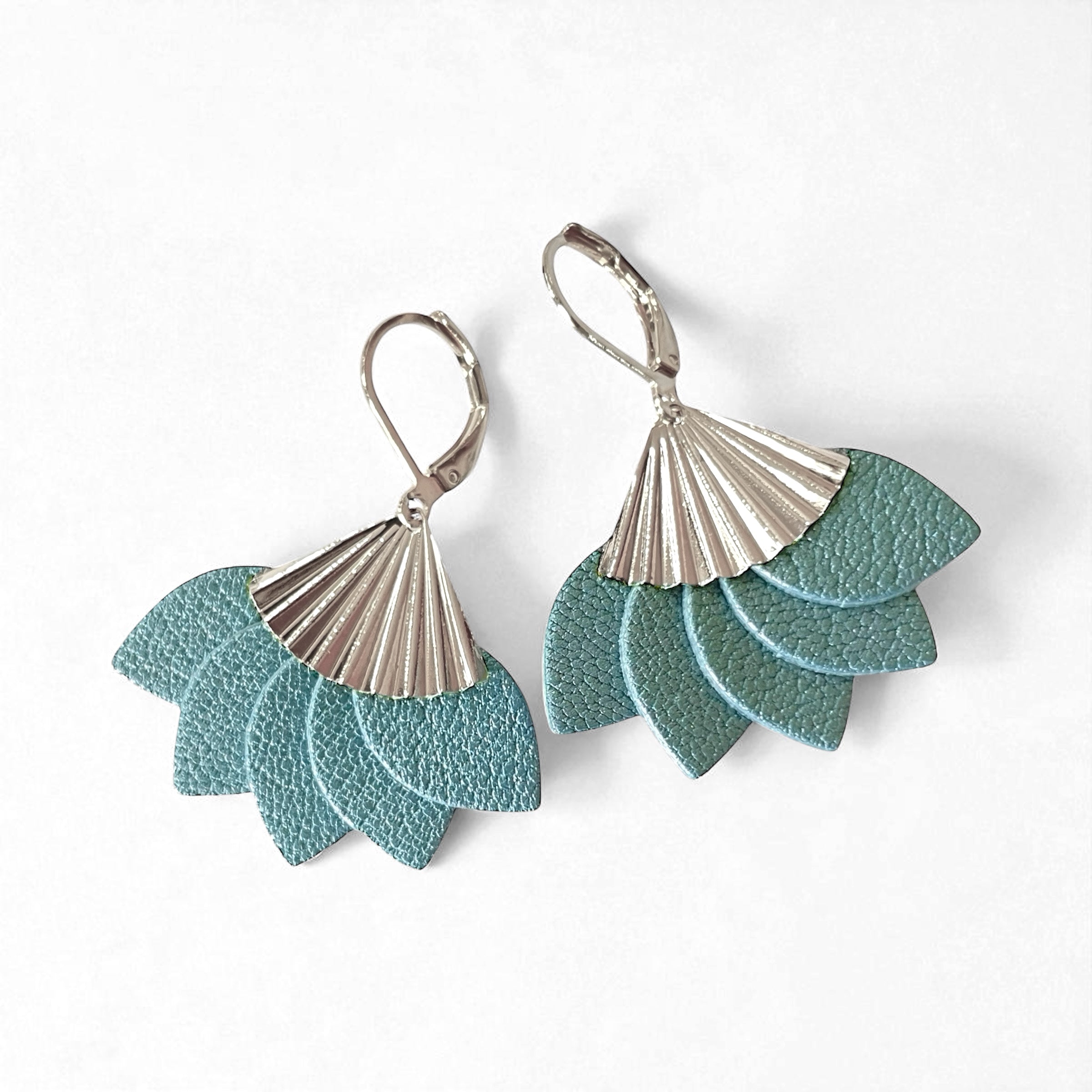 Boucles d'oreilles argentées Nune modèle Sakura en pétales de cuir bleu gris nacré sur fond blanc