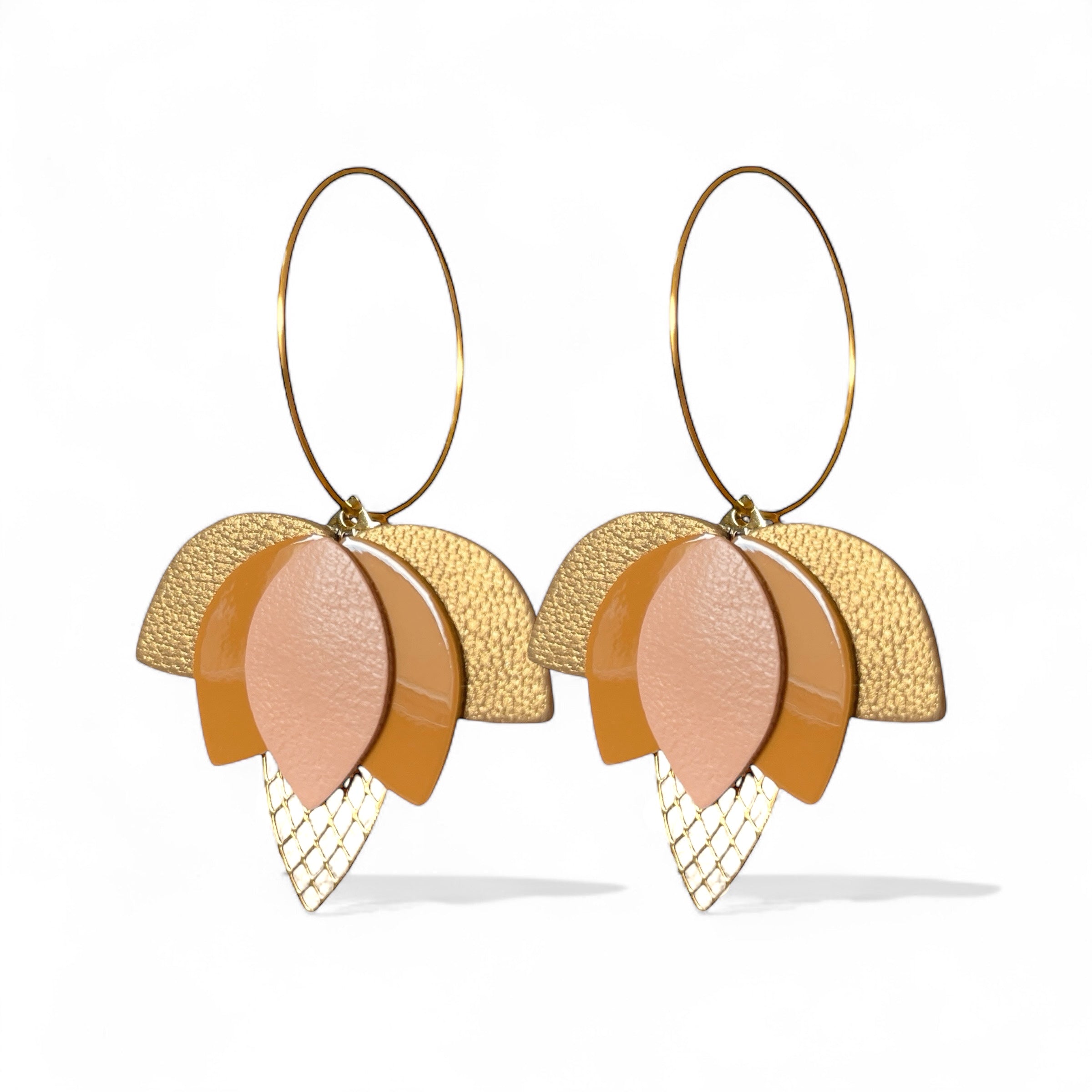 Créoles dorées en forme de fleurs de Lotus en cuirs rose pâle, safran vernis et bronze doré sur fond blanc