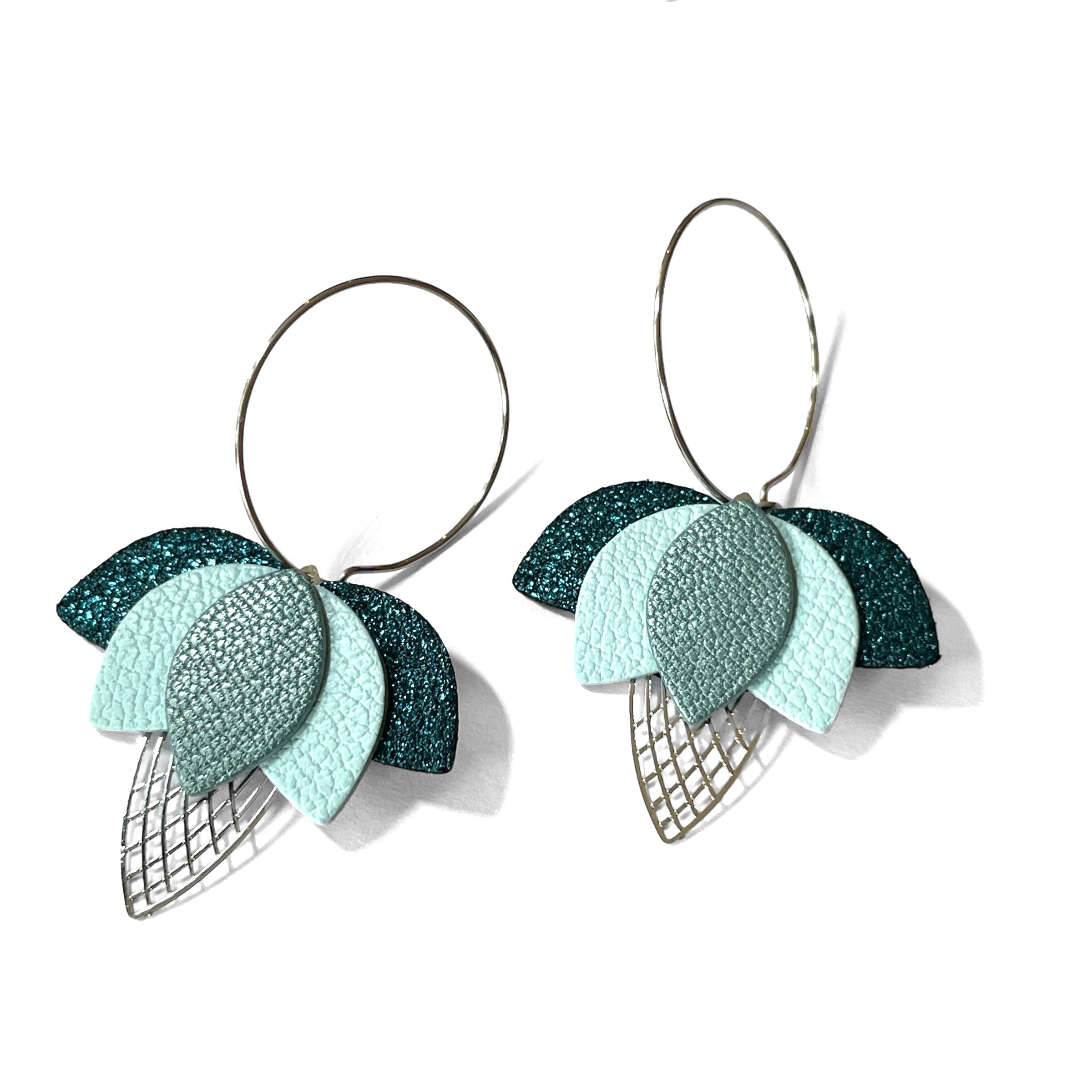 Créoles dorées en forme de fleurs de Lotus en cuirs bleu paon pailleté, bleu nuage et bleu gris nacré sur fond blanc