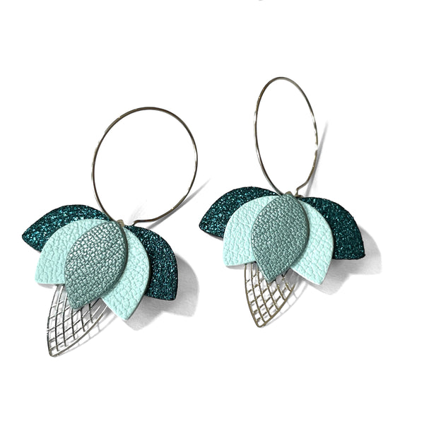 Créoles dorées en forme de fleurs de Lotus en cuirs bleu paon pailleté, bleu nuage et bleu gris nacré sur fond blanc