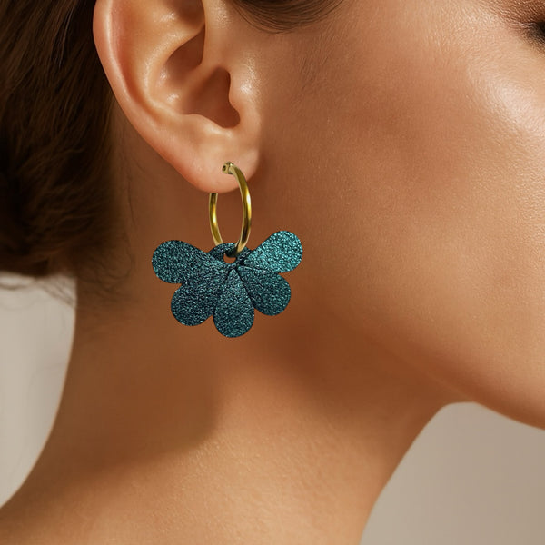 Boucles d'oreilles créoles dorées avec pendentifs en cuir bleu paon pailleté, portées à l'oreille