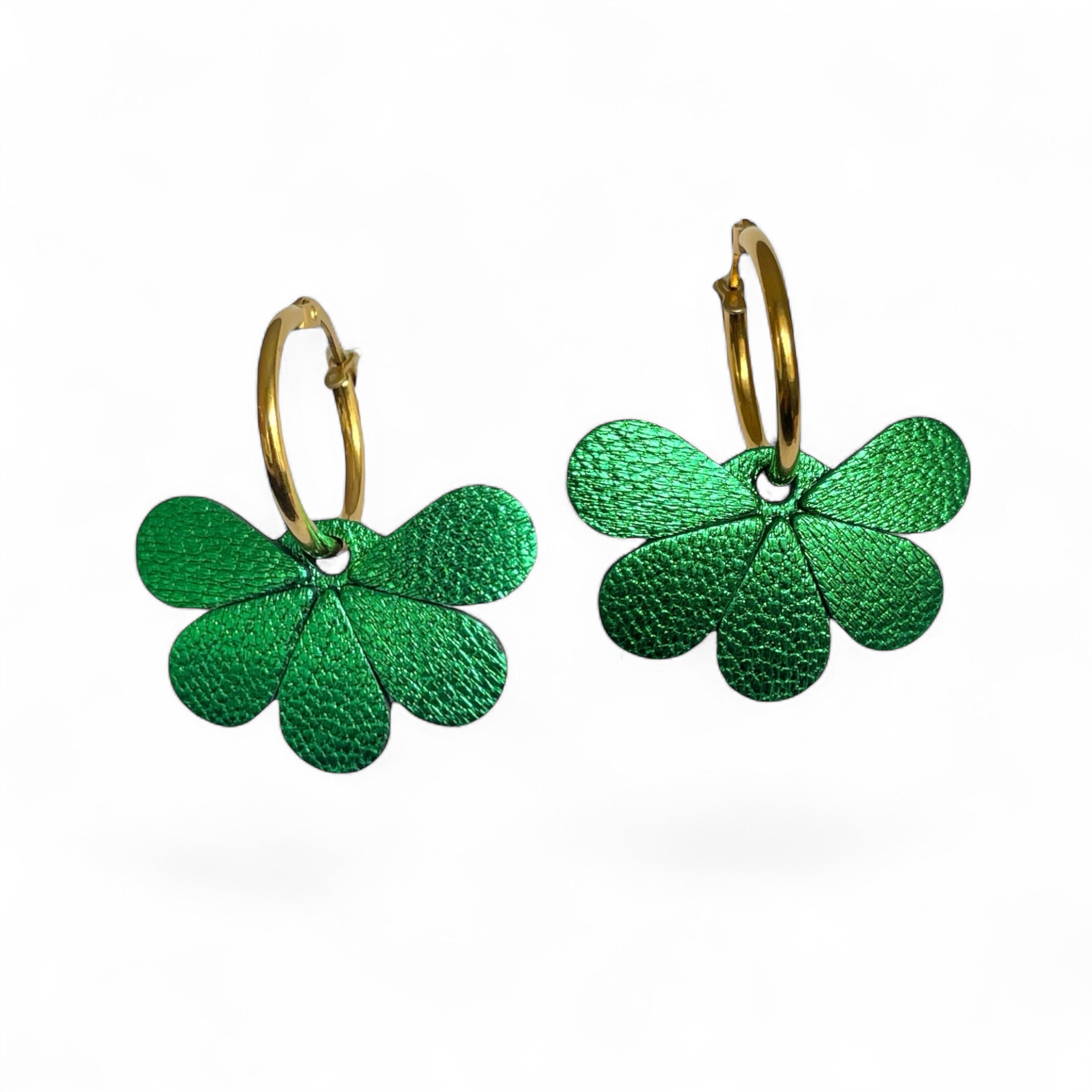 Boucles d'oreilles créoles dorées avec pendentifs en cuir vert métallisé en forme de fleurs, sur fond blanc