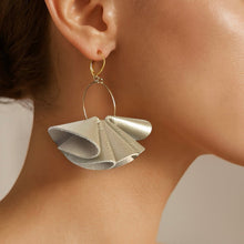 Charger l&#39;image dans la galerie, Grandes boucles d&#39;oreilles dorées aériennes et sculpturales en cuir plissé champagne nacré, portées à l&#39;oreille
