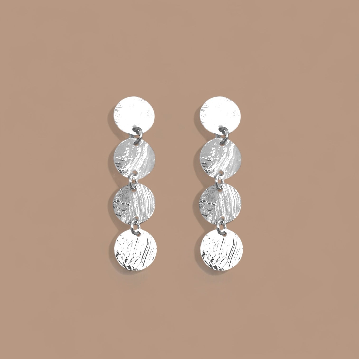 Fines puces d'oreilles pendantes en chapelet de 4 petits sequins ronds en métal martelé argenté, sur fond beige