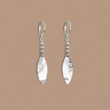 Charger l&#39;image dans la galerie, Boucles d&#39;oreilles argentées fines pendantes longues en pointes, sur fond beige
