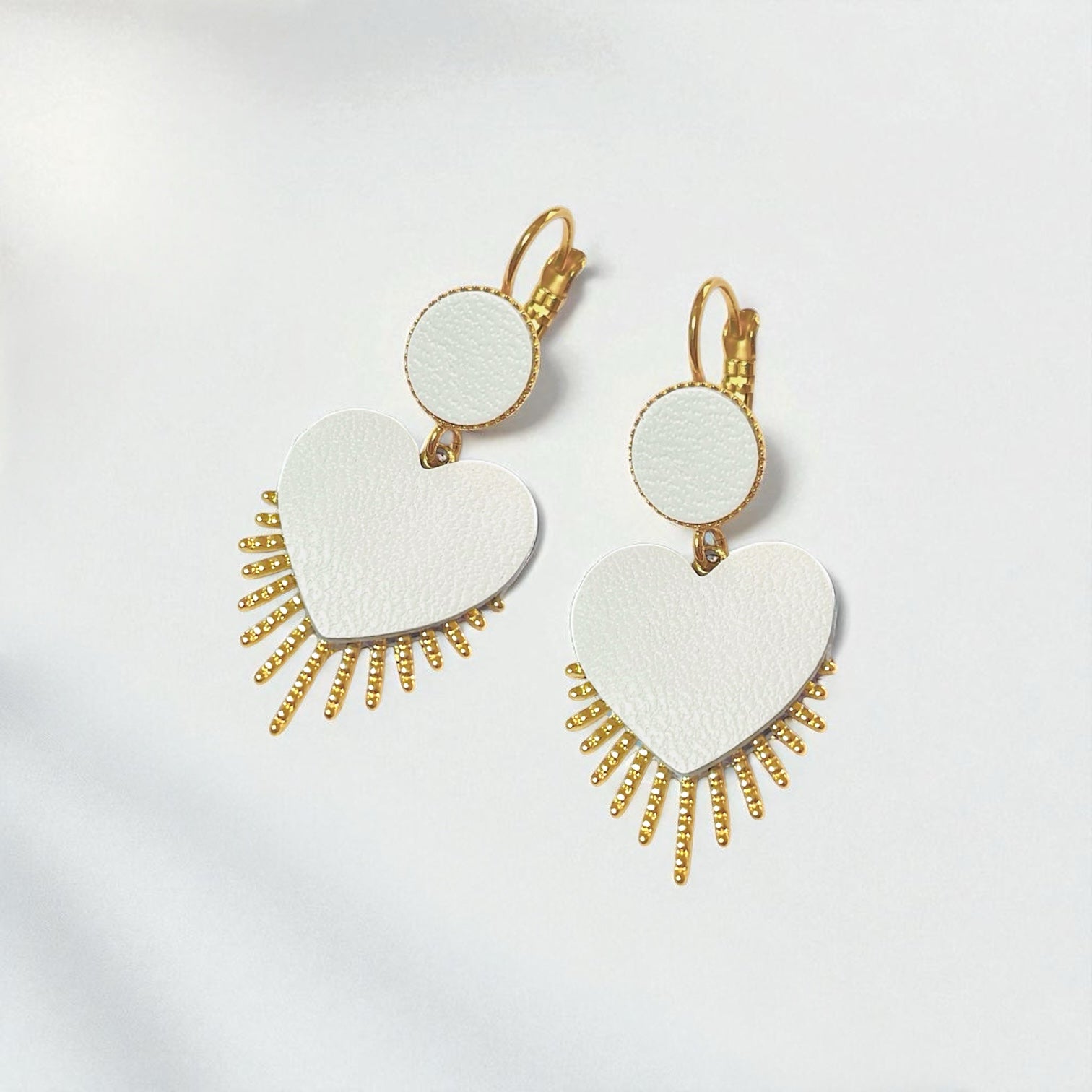 NUNE Boucles d'oreilles dorées Vénus en forme de cœurs style ex-voto en cuir blanc satiné sur fond blanc