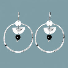 Charger l&#39;image dans la galerie, Grandes boucles d&#39;oreilles créoles en métal martelé argenté et pierres naturelles de tourmaline noire accrochée à une demi-lune, sur fond bleu gris
