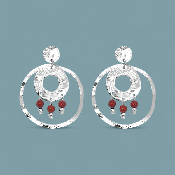 Grandes boucles d'oreilles puces créoles dorées pendantes longues rondes avec double anneau et petites perles en mokaïte acajou, sur fond bleu gris