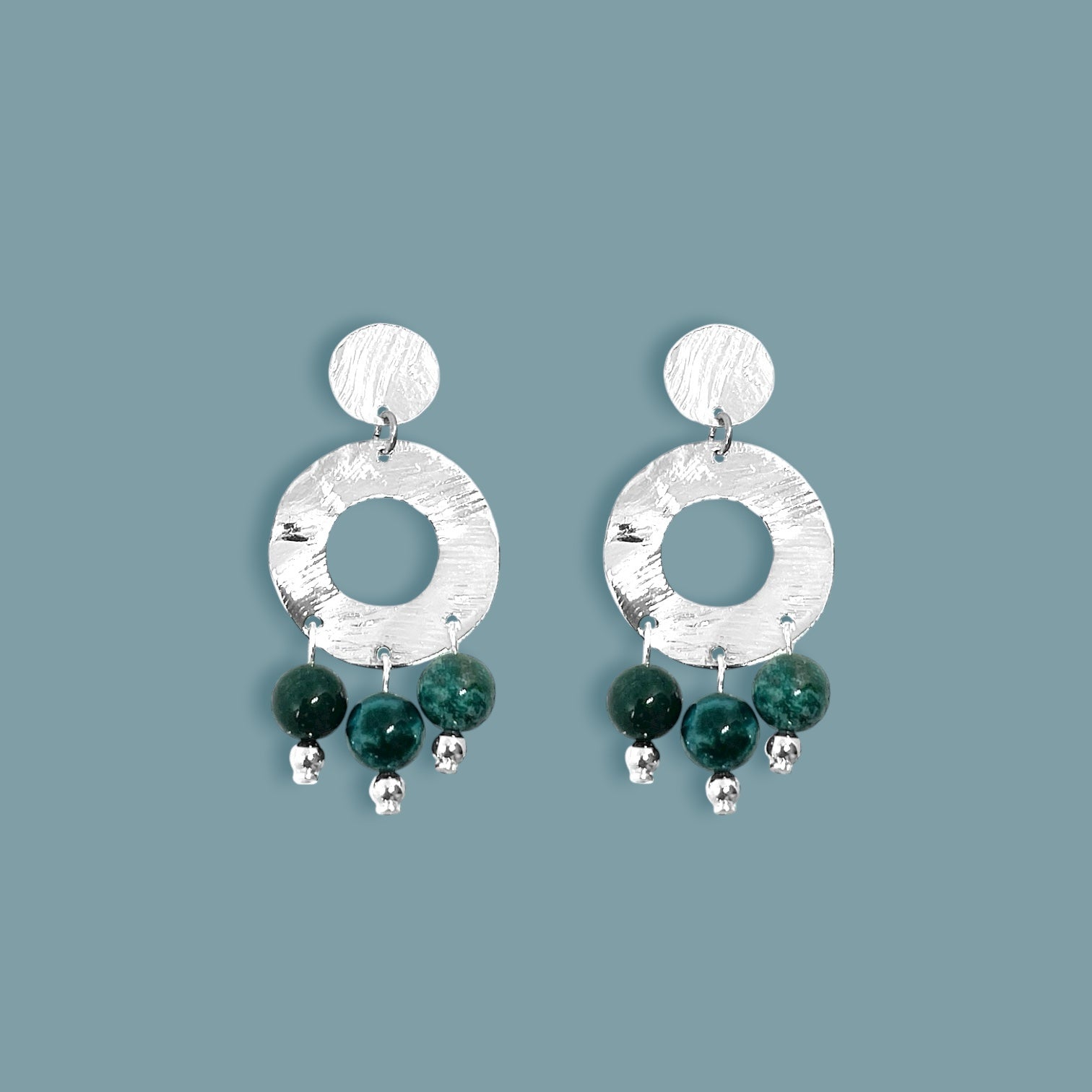 Petites boucles d'oreilles créoles à puces de forme ronde en métal martelé argenté et pierres naturelles de Jaspe océan vert foncé, sur fond bleu gris