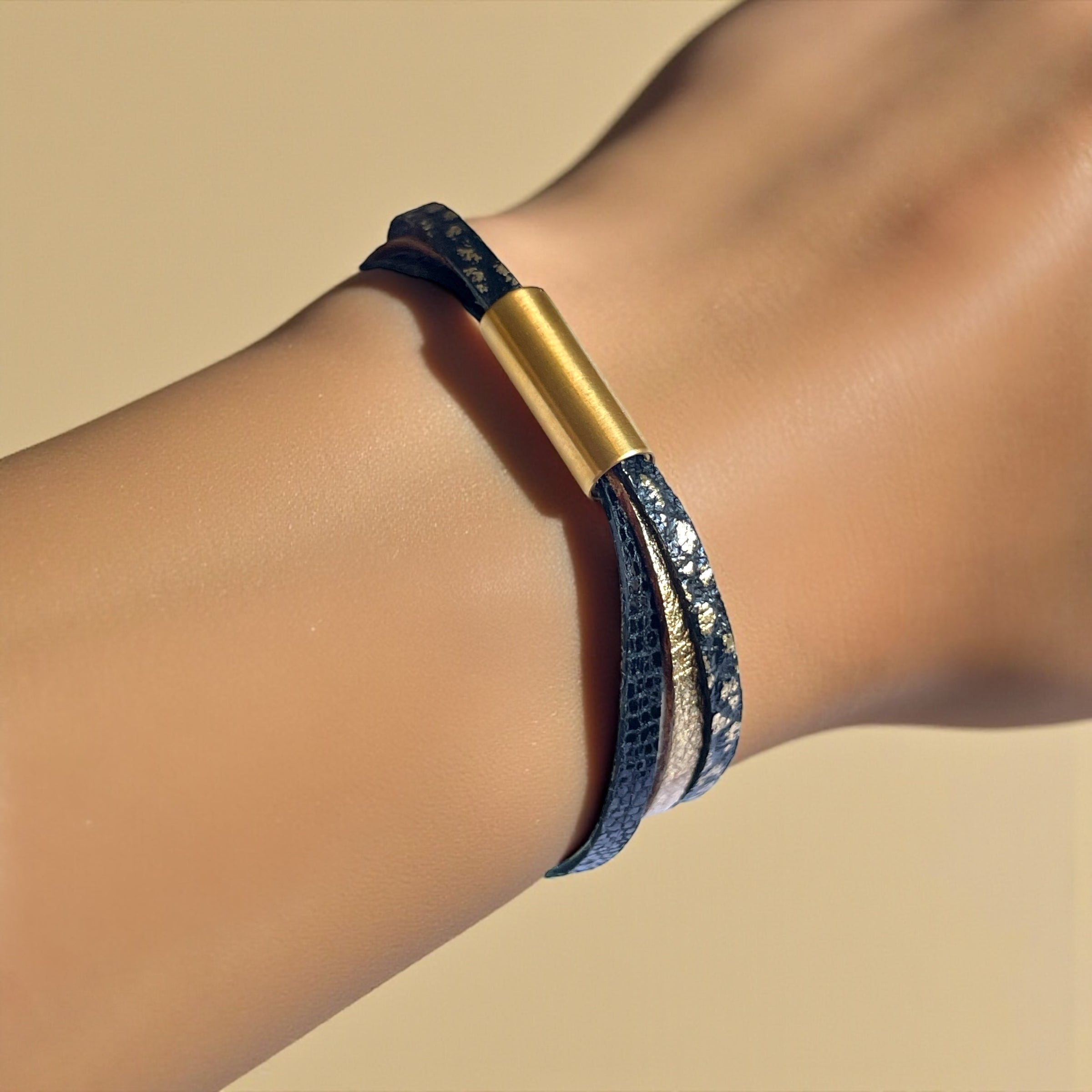 Cielo Bracelet femme tricolore à 3 liens avec fermoir aimanté doré, en cuirs doré, noir grainé or et noir brillant façon serpent, porté au poignet, sur fond beige