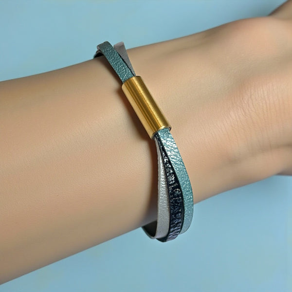 Cielo Bracelet femme tricolore à 3 liens avec fermoir aimanté doré, en cuirs bleu gris nacré, bleu glacier métallisé grainé, et champagne nacré, porté au poignet, sur fond bleu