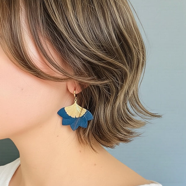 Boucle d'oreille dorée Nune modèle Ginka en cuir bleu marine satiné portée à l'oreille par une jeune femme