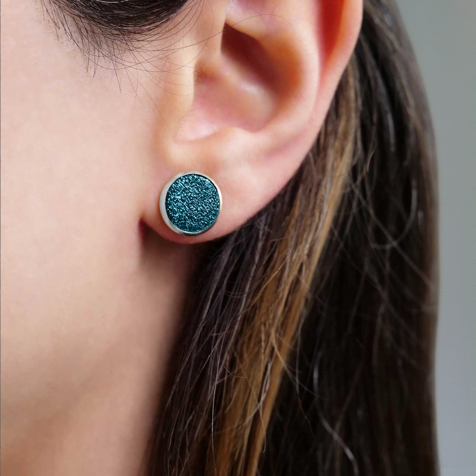 Puces d'oreilles argentées rondes Nune modèle Ilis argenté avec pastilles de cuir saphir pailleté, porté à l'oreille