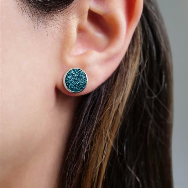 Puces d'oreilles argentées rondes Nune modèle Ilis argenté avec pastilles de cuir saphir pailleté, porté à l'oreille