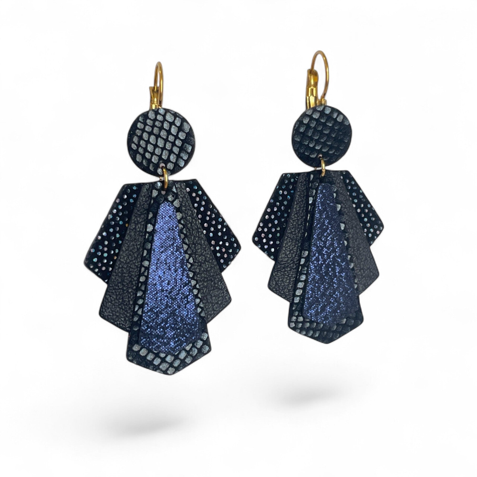 Grandes boucles d'oreilles dorées au design art déco, en cuirs noir petit grain, noir à pois holographiques, noir satiné et bleu marine pailleté, sur fond blanc