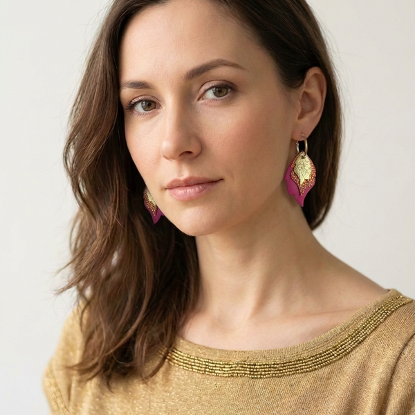 Créoles dorées avec 3 pendentifs modulables en forme de flammes en cuirs doré brillant, orangé or façon serpent et fushia, portées à l'oreille par une femme brune