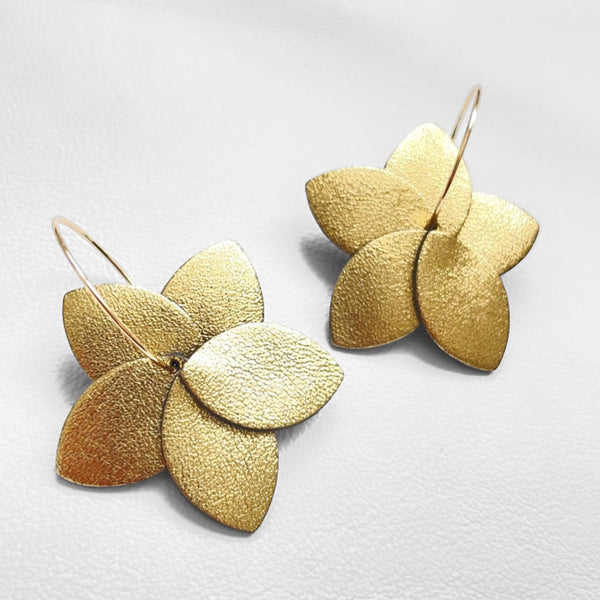 Nune boucles d'oreilles créoles Tiara en cuir doré satiné et anneaux dorés, sur fond blanc