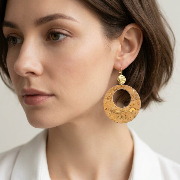 Femme brune portant des grandes boucles d'oreilles créoles Zoa rondes au style vintage en liège doré antique