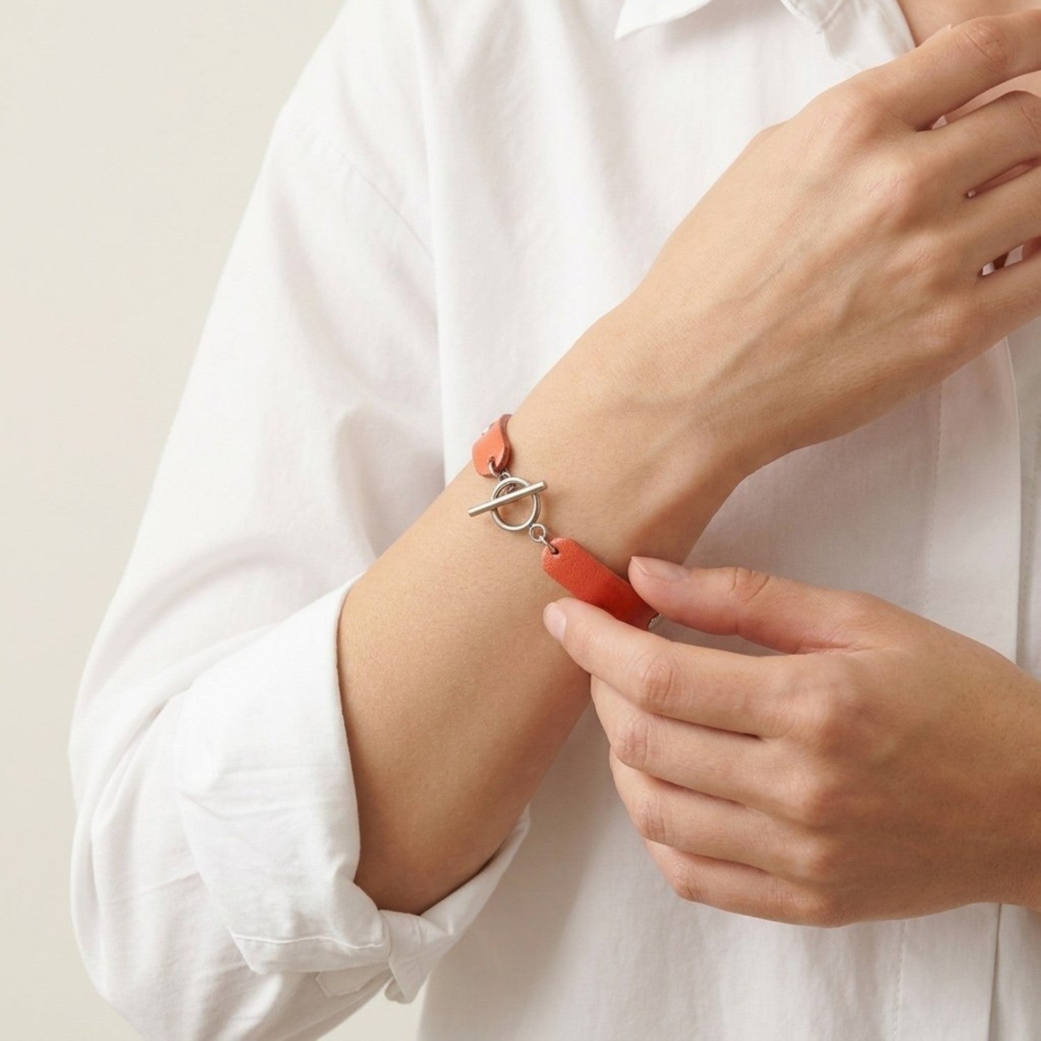 Bracelet argenté empilé en cuirs bicolore corail nacré et argent brillant froissé, porté au poignet