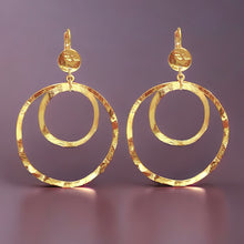 Charger l&#39;image dans la galerie, Grandes boucles d&#39;oreilles créoles dorées à double anneau en métal martelé, avec attaches-dormeuses, sur fond violet
