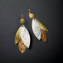 Charger l&#39;image dans la galerie, Boucles d&#39;oreilles modèle Ombline de la marque Nune, avec dormeuses dorées et pétales de cuirs trois Ors sur fond noir
