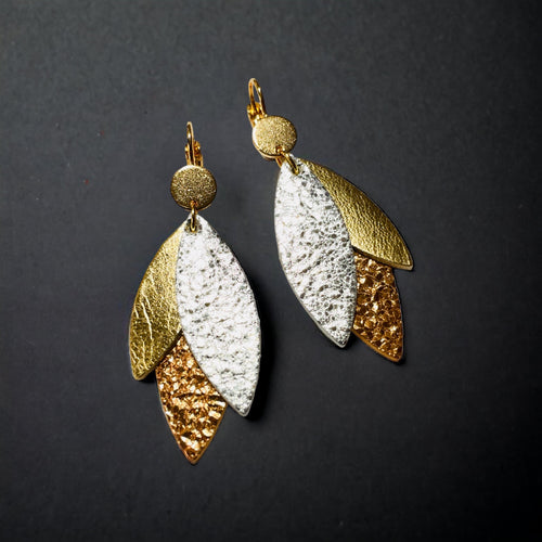 Boucles d'oreilles modèle Ombline de la marque Nune, avec dormeuses dorées et pétales de cuirs trois Ors sur fond noir