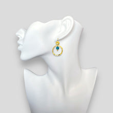 Charger l&#39;image dans la galerie, Petites boucles d&#39;oreilles créoles dorées pendantes rondes avec perles d&#39;apatite bleue, portées à l&#39;oreille sur un buste blanc
