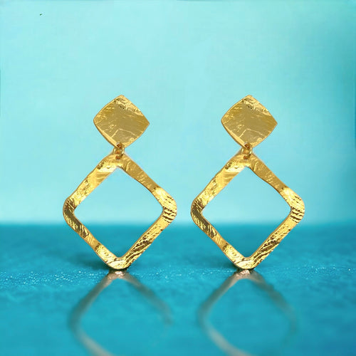 Boucles d'oreilles puces dorées à l'or fin en métal martelé avec pendentif en forme de losange, sur fond bleu