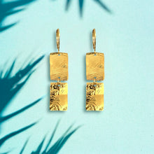 Charger l&#39;image dans la galerie, Boucles d&#39;oreilles pendantes composées de 2 rectangles en métal martelé doré à l&#39;or fin, sur fond bleu ombragé
