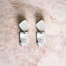 Charger l&#39;image dans la galerie, Petites puces d&#39;oreilles losanges avec pendant rectangulaire en métal martelé argenté, sur fond marbre rosé
