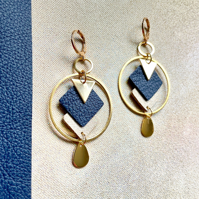 Boucles d'oreilles Nune modèle Créoles Adamante Or en cuir bleu marine grainé et laiton doré à l'or fin sur fond beige irisé