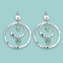 Charger l&#39;image dans la galerie, Grandes boucles d&#39;oreilles créoles en métal martelé argenté et perles minérales naturelles d&#39;amazonite, de forme ronde, avec doubles anneaux, sur fond vert pastel
