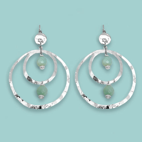 Grandes boucles d'oreilles créoles en métal martelé argenté et perles minérales naturelles d'amazonite, de forme ronde, avec doubles anneaux, sur fond vert pastel