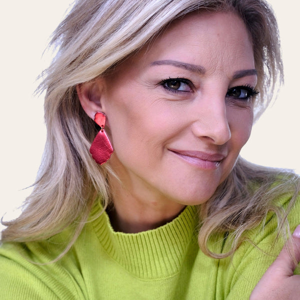 Femme blonde portant les boucles d'oreilles rouge métallisé de style rétro baroque