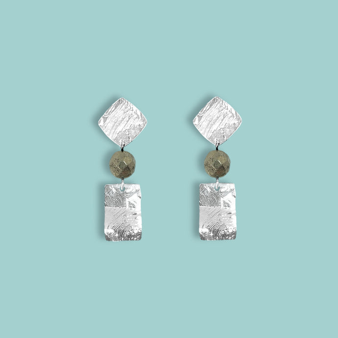 Petites boucles d'oreilles puces en métal martelé argenté et perles de Pyrite, de forme losanges et rectangles, sur fond vert pastel